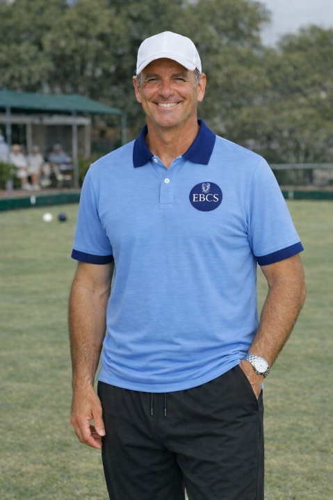 A coach wearing the new blue EBCS polo shirt on the green
